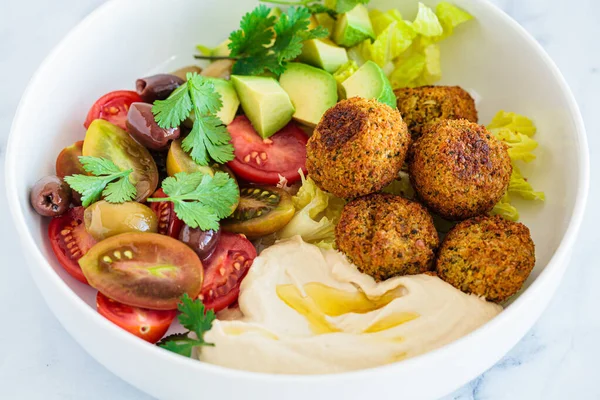 Marul, domates, avokado, humus ve zeytinli falafel salatası tabağı. Sağlıklı vejetaryen yemekleri, İsrail mutfağı.