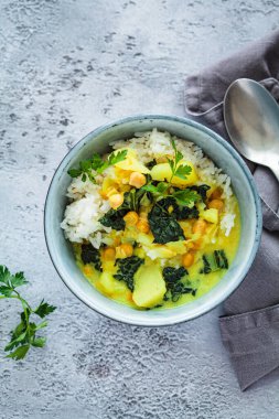 Vejetaryen nohut patates körisi, pirinçli ve lahanalı mavi kase, gri arka plan, üst manzara. Alternatif bitki temelli çevre dostu gıda konsepti.