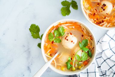 Beyaz bir kasede erişte ve sebzeli patates köftesi çorbası, beyaz arka plan, üst manzara. Vejetaryen gıda konsepti.