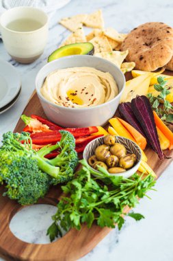 Humus, sebze, meyve, zeytin, pide ve kraker ile vejetaryen atıştırma tahtası. Sağlıklı yemek, vejetaryen diyeti, parti konsepti.