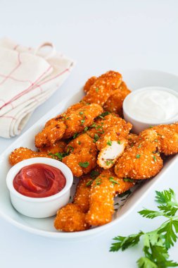 Beyaz tabakta domates ve krema soslu ev yapımı tavuk külçeleri, yakın plan, beyaz arka plan. Ev yapımı alternatif fast food.