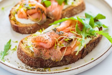 Krem peynirli, somonlu, yağlı ve roka kaplı kahvaltı tostu, beyaz arka plan, yakın plan. Keto diyet tarifi.