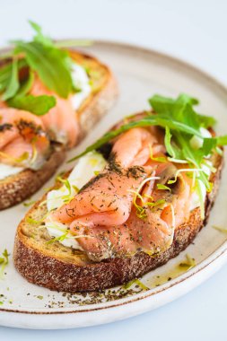 Krem peynirli, somonlu, yağlı ve roka kaplı kahvaltı tostu, beyaz arka plan, yakın plan. Keto diyet tarifi.