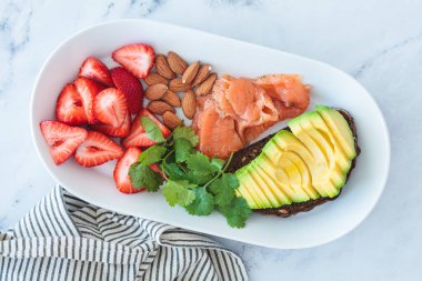 Kahvaltıda avokado tostu, somon, fındık ve taze çilek..