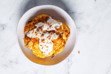 Tam kavrulmuş baharatlı karnabahar tahini soslu ve karamelli soğan, üst manzara..