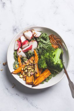 Lahana, brokoli, fırında patates, turp ve kırmızı pesto ile vejetaryen yemek kasesi..