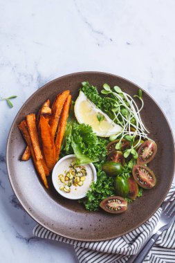 Vejetaryen salata kasesi fırında patates, domates, fındık, tahini sosu ve lahanası, beyaz mermer arka plan, üst manzara..