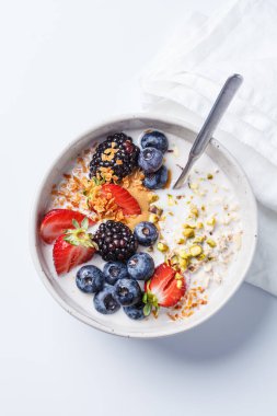 Taze böğürtlen ve fındıklı bir gecelik yulaf ezmesi, beyaz arka plan, üst manzara. Sağlıklı kahvaltı kavramı.