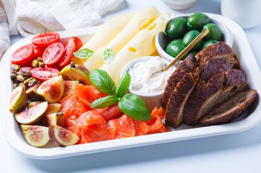 Somon, peynir, zeytin, ekmek ve sebze kahvaltı tabağı, beyaz arka plan..