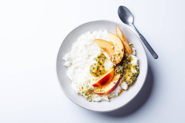 Şeftalili sütlü yulaf lapası ve beyaz arka planda tutku meyvesi. Yaz sağlıklı kahvaltı konsepti.