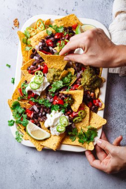 Guacamole soslu vejetaryen nacho yiyen bir kadın, parti için siyah fasulye ve salsa sosu..