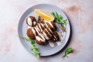 Gri bir tabakta tahini soslu falafel topları, üst manzara. İsrail mutfağı kavramı.