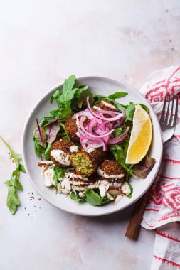 Tahini soslu falafel salatası, kırmızı soğan ve fındık turşusu. İsrail mutfağı kavramı.