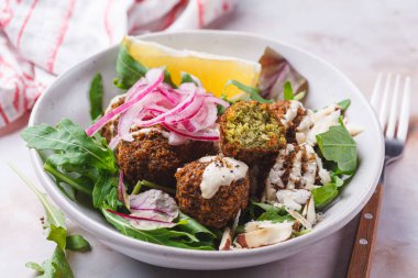 Tahini soslu falafel salatası, kırmızı soğan turşusu ve fındık, yakın plan. İsrail mutfağı kavramı.