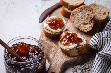 Krem peynirli ve gri arkaplanlı tostlarda soğan reçeli..