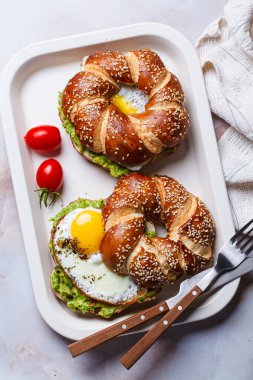 Beyaz tabakta yumurta ve avokado soslu kahvaltı çöreği..