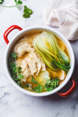 Mantar çorbasıyla Gyoza çorbası ve kırmızı bir tencerede bok choy, üst manzara. Japon mutfağı kavramı.