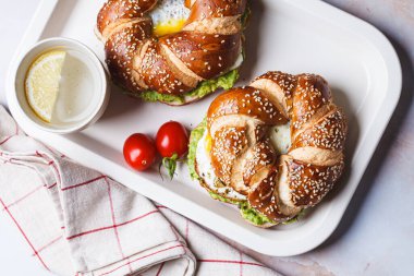 Beyaz tabakta yumurta ve avokado soslu kahvaltı çöreği..