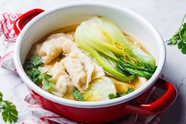 Mantar çorbasıyla Gyoza çorbası ve kırmızı bir tencerede bok choy, yakın plan. Japon mutfağı kavramı.