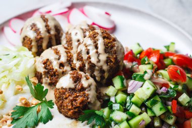 Falafel - Tahini, sebze salatası ve lahana salatası tabağında nohut topları.