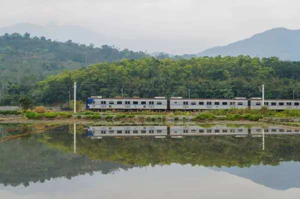 Rural Charm: Train Journey Through Verdant Fields and Hazy Mountains.