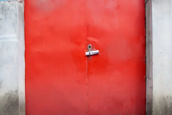 A close-up shot of an old red steel door with a rolled-up note.