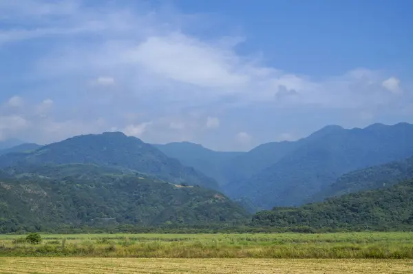 Scenic Mountain Range Under Blue Sky: A landscape featuring a series of mountains receding into the distance under a blue sky with some clouds.