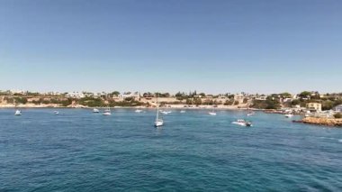 Güneşli bir Akdeniz kıyı şeridinin hava aracı görüntüsü. Yelkenli tekneler ve açık mavi deniz bir yaz günü.