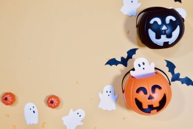 Halloween decorations on yellow background. Pumpkins, ghosts and bats Halloween background.