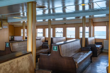 Interior of an old wooden passenger ferry cabin with vintage bench seats and sea view windows