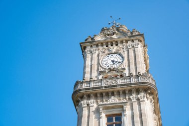 Dolmabahce Clock Tower an iconic historical landmark monument in Istanbul, Turkey. Ornate stone clock tower against a clear blue sky. Popular Ottoman architectural structure