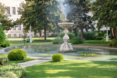 Dolmabahce Palace garden with beautiful fountain and roses in foreground, Istanbul. Historic grand Ottoman palace garden view with flowers