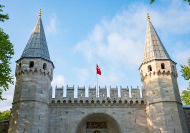 Istabul, Turkey - August 26 2025: Grand entrance of Topkapi Palace with towers and Turkish flag under blue sky. Gate of salutation. Historic Ottoman architecture, Landmark