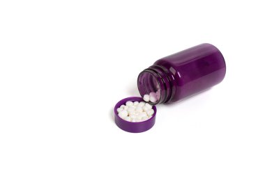 İzole edilmiş beyaz arka planda beyaz tabletli mor ilaç şişesi. İlaç şişesi ve dökülen hapların yakın çekimi. Sağlık, ilaç, bakım ve tedavi kavramı