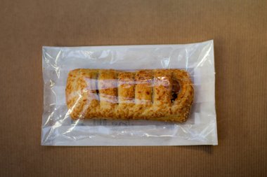 Altın bir hamur işi, çıtır çıtır bir dış görünüş sunar ve lezzetli malzemelerle doludur. Tazelik için düzgünce paketlenmiştir. Keyif almaya hazırdır..