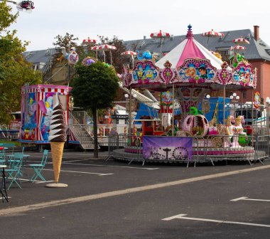 Parlak renkli karnaval gezileri ve eğlenceleri halka açık bir parkta kurulur. Aileler açık gökyüzünün altındaki renkli süslemelerle çevrili şenlikli atmosferin tadını çıkarıyorlar..
