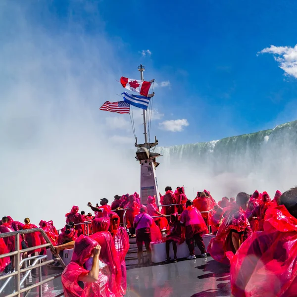 Güzel Niagara Şelalesi, ünlü şelale tekne turunda, Kanada ve Amerika bayrağı Niagara gemi direğinde yağmurluk giyen turistlerle dalgalanıyor. Yüksek kalite fotoğraf.