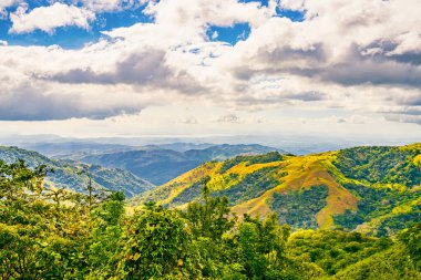 Monteverde 'nin yemyeşil yamaçları dinamik bir gökyüzü altında zengin biyolojik çeşitliliği ve Puntarenas Eyaleti, Kosta Rika' nın katmanlı dağ manzaralarını sergiliyor. Yüksek kalite fotoğraf