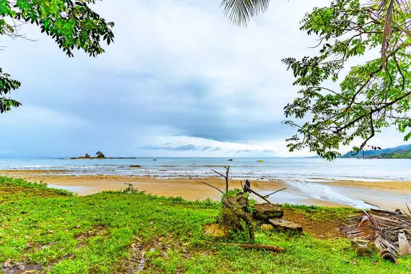 Serene Tropische Strand Scene Met Bewolkte Luchten Omlijst Door Groen Rechtenvrije Stockafbeeldingen