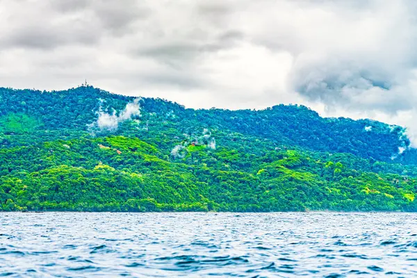 stock image Lush green hills covered with mist, meeting the calm blue ocean under a cloudy sky in Uvita, Puntarenas Province, Costa Rica. High-quality photo.