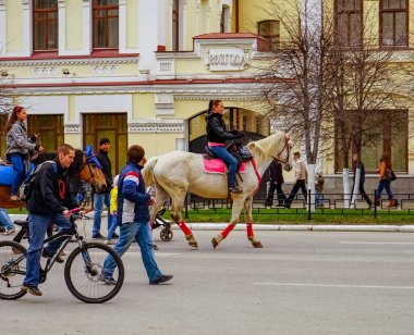 Ekaterinburg 2014 İnsanlar tarihi bir binanın önünde at binicileri ve bisikletçilerle bir şehir caddesinde eğleniyor, canlı bir şehir manzarası yaratıyorlar..