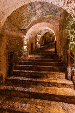 Kemerli taş tavanlı ve sıcak ışıklandırmalı tarihi yeraltı merdivenleri gizemli ve atmosferik bir ortam yaratıyor. Yüksek kaliteli fotoğraf. Ik Kil Cenote, Yucatan, Meksika.