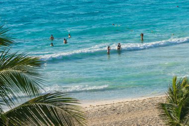 Cancun, Meksika - 6 Ocak 2022: İnsanlar güneşli Cancun Yüksek kalite fotoğrafıyla kumlu sahil boyunca yüzüyor ve turkuaz suların keyfini çıkarıyorlar.