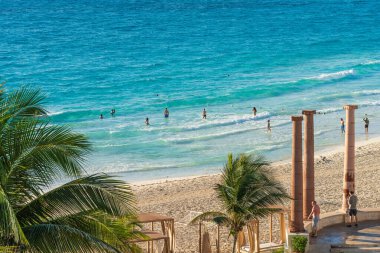 Cancun, Meksika - 6 Ocak 2022: İnsanlar Cancun 'un turkuaz sularının ve yumuşak kumlarının keyfini çıkarıyorlar, palmiye ağaçları, güneş ışığı dalgaları ve tropikal plaj titreşimleri ile çevrili yüksek kaliteli fotoğraf