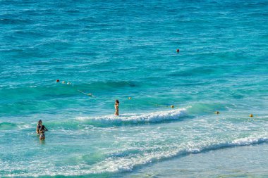 Cancun, Meksika - 6 Ocak 2022: Cancun 'daki berrak turkuaz dalgaların tadını çıkaran kadınlar, plajın yakınlarındaki sığ sularda dinleniyor ve yüksek kaliteli fotoğraf çekiyorlar..