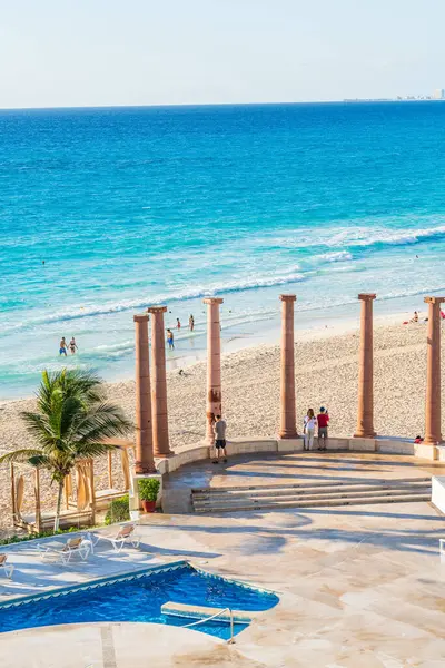 Cancun, Meksika - 6 Ocak 2022: Turistler, Cancun 'da güneşli bir günde, arka planda yüksek kaliteli bir fotoğraf havuzu ve turkuaz dalgalarıyla okyanus manzarasına taş sütunlar aracılığıyla hayran kalırlar..