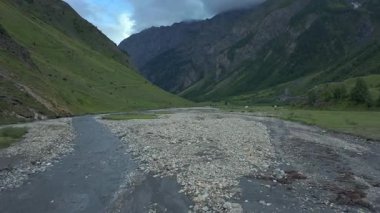 Sisli bir dağ vadisi ve yemyeşil tepelerle çevrili akan bir nehrin insansız hava aracı görüntüleri. Yumuşak ışık ve bulutlar barışçıl, sinematik bir atmosfer yaratır. Belgeseller, seyahat videoları ya da çevre filmleri için mükemmel.