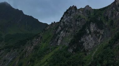 Bulutlu, yağmurlu bir gökyüzünün altında dramatik kayalık dağ. Karamsar ve atmosferik, manzara, doğa, dağlar, seyahat ve sinema projeleri için mükemmel.