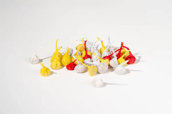 A pile of small, colorful firecrackers, commonly known as Pop-Pops or snappers, lying on a plain white background.