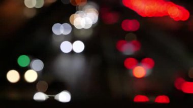 Gecenin karanlığında bulanık arkaplanda güzel, ışıltılı bir bokeh. Şehir caddesindeki trafik sıkışıklığında araba ışıklarından yuvarlak renkli bokeh parlıyor. Bulanık yüzünden bulanık. Odaklanmamış şehir ışıkları.